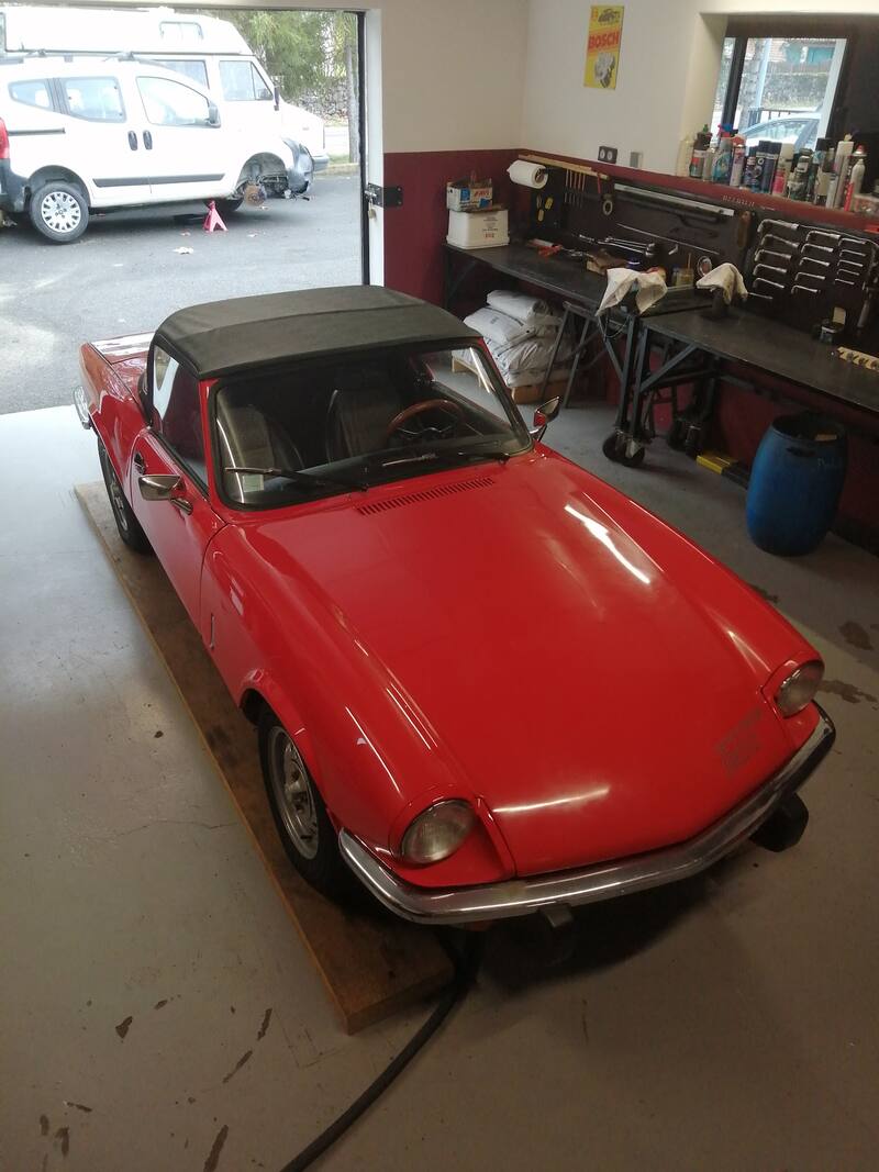 Triumph Spitfire rouge, capote noire, sur cales dans l'atelier